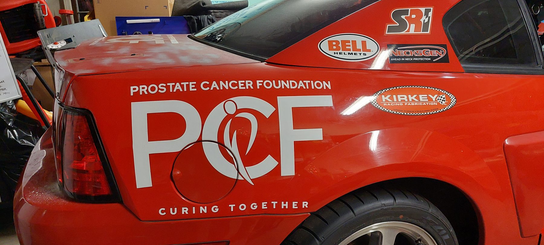 The PCF mark applied at large scale to the rear quarter panel of a race car.
